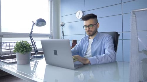 Young Adult Working on Laptop in Modern Office