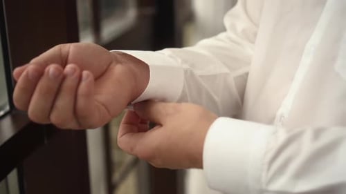 Man Fastens Cufflink on White Dress Shirt Sleeve