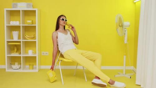 Stylish Woman Relaxing in Yellow Room on Phone
