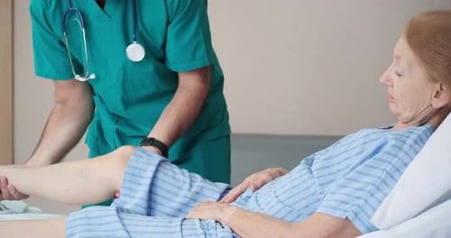 Medical Professional Examining Leg of Senior Patient