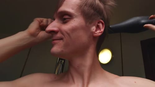 Man Styles Hair with Comb and Hair Dryer