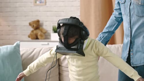 Girl Experiencing Virtual Reality with Help of Adult