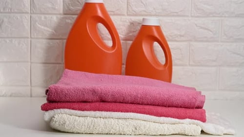 Folding Colorful Towels Near Laundry Detergent Bottles