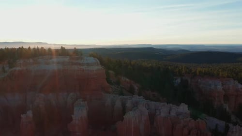 sunset backlighting a huge valley in Utah countryside. Red rock canyon formations and forest. Aerial