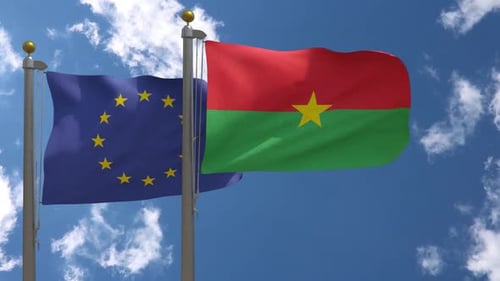 European Union and Burkina Faso Flags Waving on Flagpoles Under Blue Sky