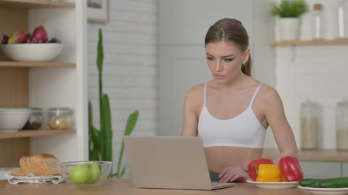 Woman Using Laptop in Bright Kitchen with Healthy Food