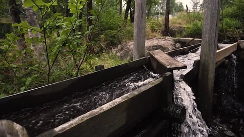 Wasser fließt in Zeitlupe durch alte hölzerne Flussmühle