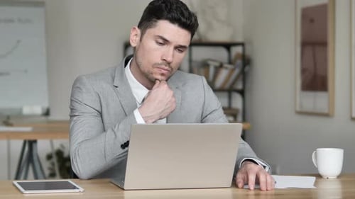 Young Adult Businessman Thinking and Working at Laptop