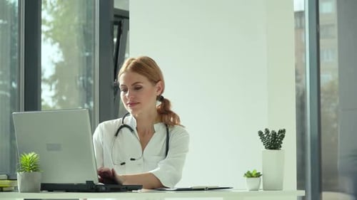 Woman Doctor Typing on Laptop in Office