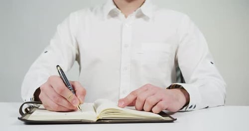 Hand Writing in Notebook at Desk