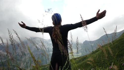 Man Hiker with Long Hair Raises Hands Up in Mountains Enjoying Beautiful View and Surrounding Wild