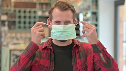 Adult Man Puts on a Surgical Face Mask
