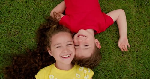 Happy Little Brother and Sister Lies on Green Grass