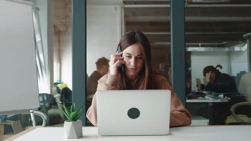 Woman Answers Phone While Working on Laptop