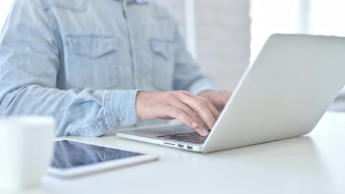 Nahaufnahme eines jungen Mannes mit Laptop im modernen Büro