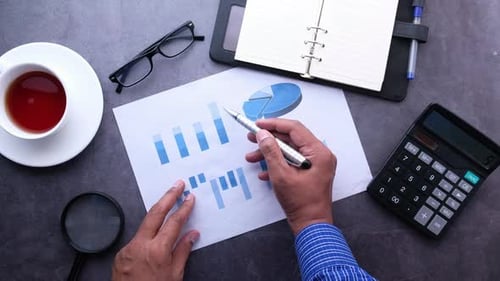 Draufsicht eines Geschäftsmannes Hand mit Stift bei der Analyse des Finanzdiagramms