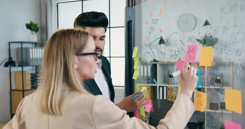 Professionals Collaborate on Whiteboard in Modern Office