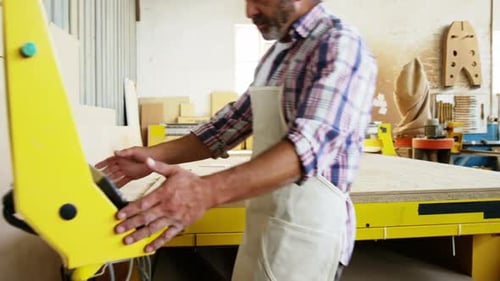 Carpenter using his machine and smiling for camera