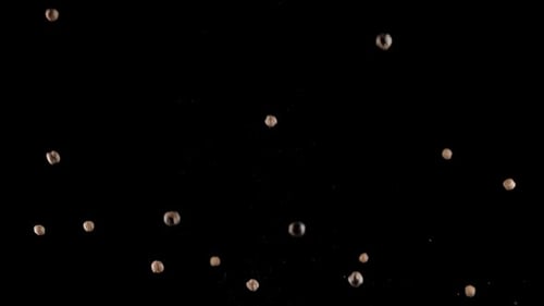 Small brown sphere drops bouncing on black background