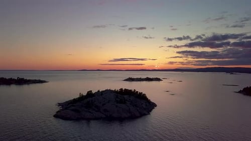 Rocky Pine Tree Islands in Big Lake just after Sunset, Drone Aerial Wide Dolly In. Colorful Clouds i