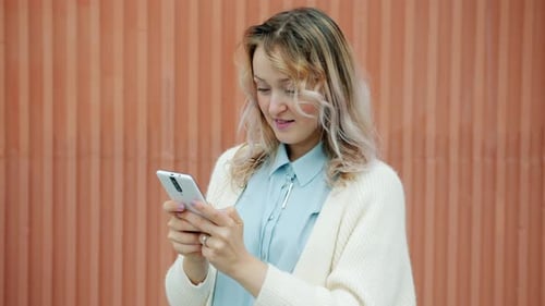 Woman Using Mobile Phone in Front of Patterned Wall