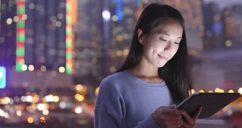 Woman Using Tablet at Night in the City