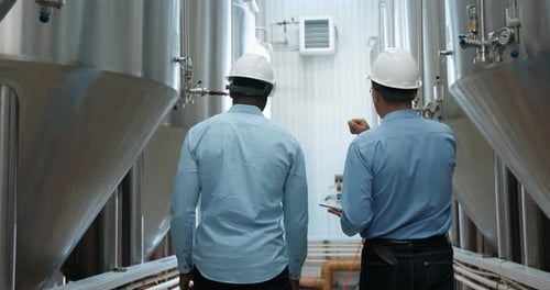 Two Industry Engineers Walk in Factory Use Tablet and Discuss Work