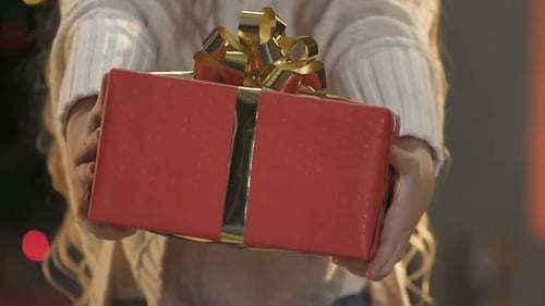 Holding Out a Christmas Gift with Gold Ribbon