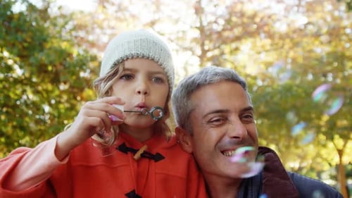 Girl Blowing Bubbles with Smiling Adult