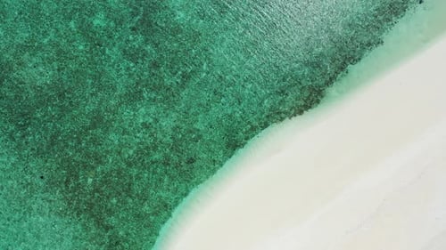 Daytime overhead island view of a white sandy paradise beach and blue water background in vibrant 4K