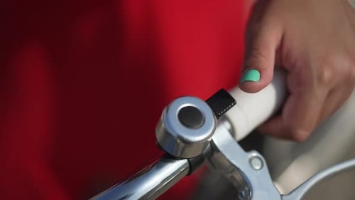 Closeup Female Hand Ringing Bicycle Bell in Slow Motion in Sunbeam Outdoors