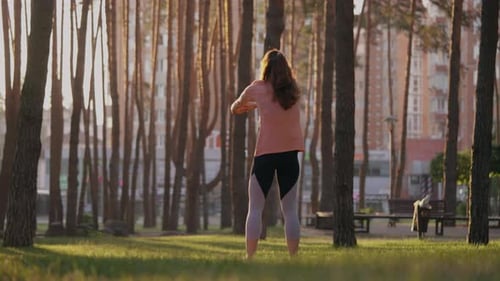 Woman Stretching and Exercising in the Park at Sunrise