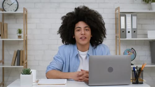 Young Man Talking at Desk with Laptop