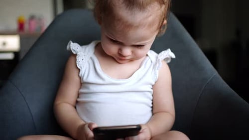 Child Sits Looking at Mobile Phone