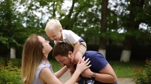 Smiling Family Smiles Together in Park on Sunny Day