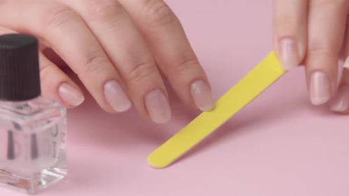 Woman Filing Nails with Yellow Nail File