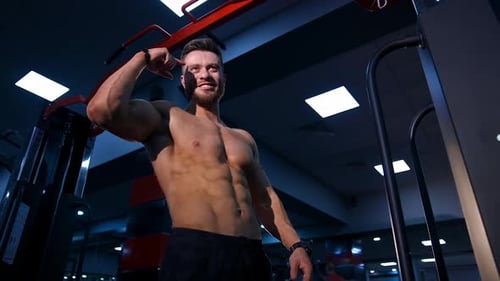 Muscular Man Smiles and Flexes Bicep in Gym