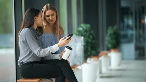 Two Friends Using Phone Together in an Urban Setting
