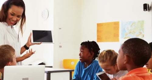 Teacher teaching school kids on digital tablet in classroom