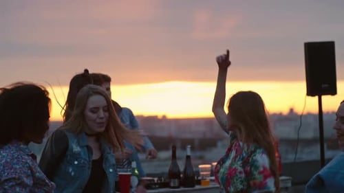 Friends Dance at Rooftop Party During Golden Sunset