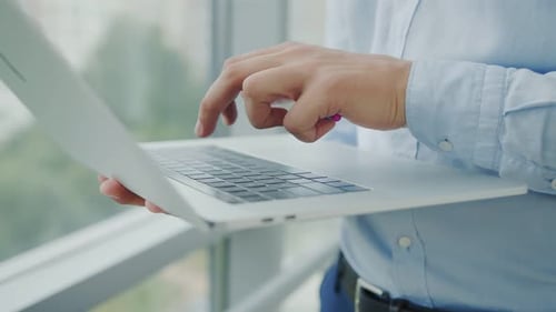 Close Up of Man Typing on Laptop Keyboard. The Man's Fingers Press on the Laptop Keys.