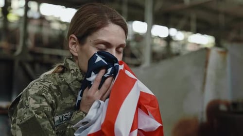 Woman in Camouflage Holds American Flag Close