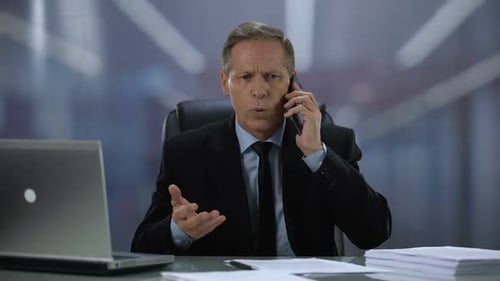 Man in Suit Talking on Phone at Desk