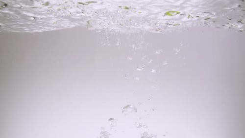 Limes Falling into Water creating Bubbles
