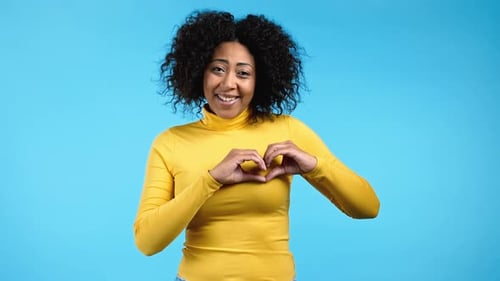 Woman Making Heart Shape with Hands on Blue