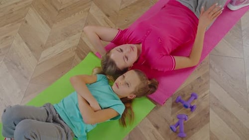 Woman and Child Lying on Yoga Mats Indoors