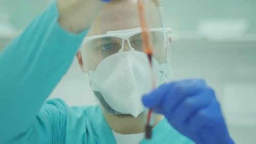 Análisis de sangre. El doctor en mascarillas y gafas médicas está realizando investigaciones en el laboratorio. Médico masculino o