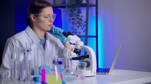 Scientist Examining Samples Under a Microscope in a Lab