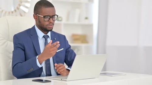 African Businessman Doing Video Call on Laptop in Office