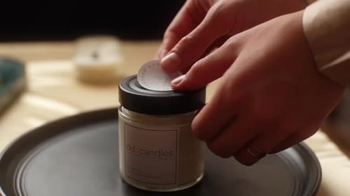 Hands Place Sticker on Candle Jar Lid